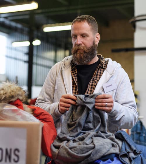 Portrait of volunteers sorting out donated clothes in community charity donation center.