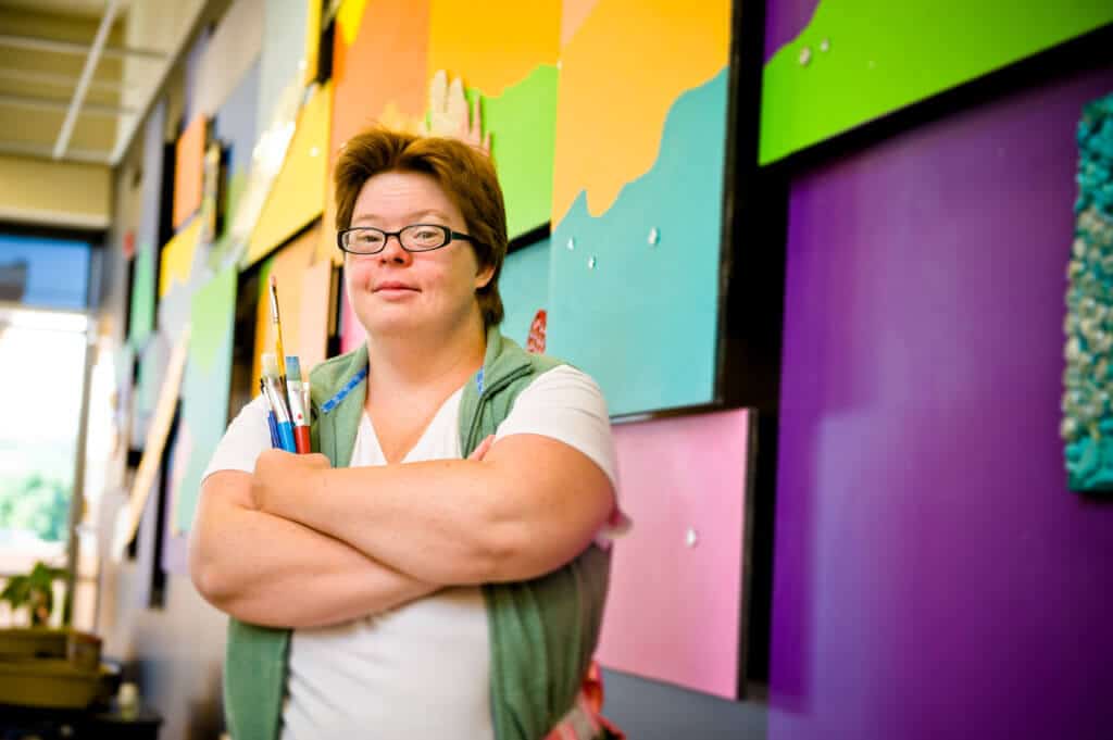 man standing with arms crossed in front of colorful wall