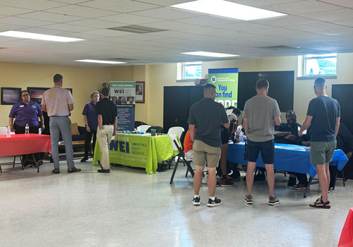 Community Resources People gather around tables set up for a job fair in the community.