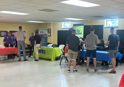 Community Resources People gather around tables set up for a job fair in the community.