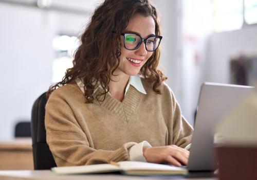 Young woman wearing glasses completed Google AI training course on laptop.