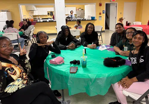 Youth Services Group of young women gathered around a table enjoying time together.