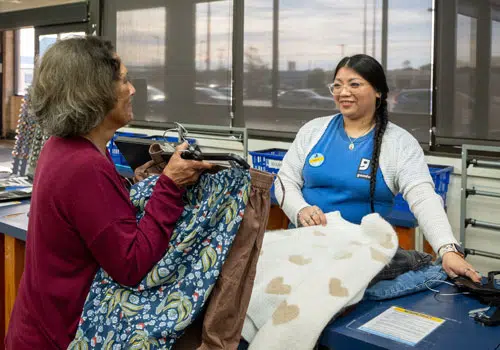 Goodwill employee and volunteer sort clothing in store.
